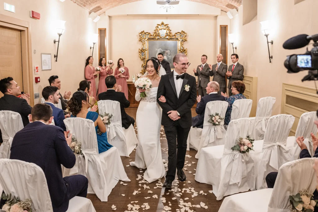 Due sposi, al termine del loro rito civile, escono dalla sala tra gli applausi degli invitati